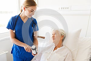 Nurse giving medicine to senior woman at hospital