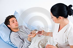 Nurse giving pills to a male patient