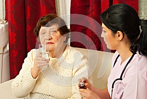 Nurse giving pills and water to senior