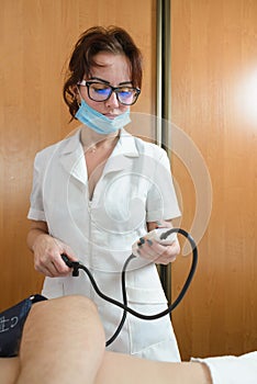 Nurse in glasses measures the pressure