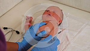Nurse in gloves vaccinating premature baby in hospital. intensive care unit, naneonatology center. Closeup. hand of