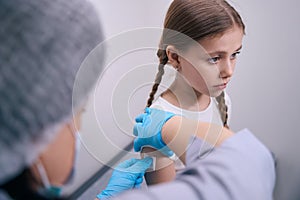 Nurse glues a patch on the hand of young patient