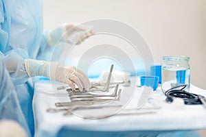 A nurse hands surgical instruments to a doctor during maxillofacial surgery operation. Sterile medical tools