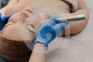 Nurse hands use injection dermapen technology to calm woman face, patient reclining on couch in spa, beauty treatments photo