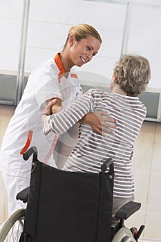 Nurse helping disabled elderly woman get up