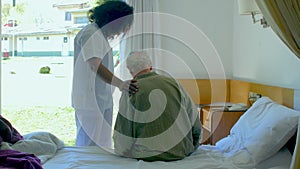 Nurse helping elderly man leaving hospital bed