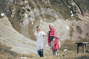 Nurse helping elderly senior man to walk on frash air