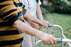 Nurse helping elderly woman hands holding walker trying to walking at outdoor,Care nursing home concept,Physical therapy