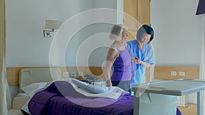 Nurse helping elderly woman leaving her hospital bed