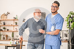 Nurse helping his senior patient to walk with a cane