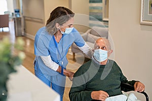 Nurse helping man in wheelchair at care facility centre