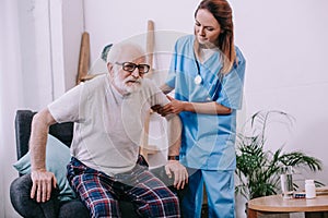 Nurse helping old man to stand up