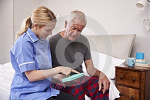 Nurse Helping Senior Man To Organize Medication On Home Visit