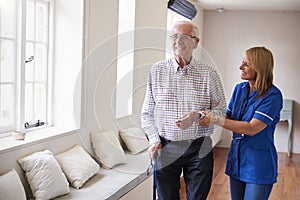 Nurse helping senior man walk using a walking stick