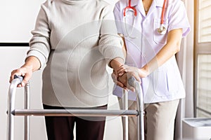 Nurse helping senior woman hand holding walker trying to walk,Care nursing home concept