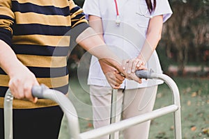 Nurse helping senior woman hands holding walker trying to walking at outdoor,Care nursing home concept,Physical therapy