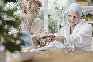 Nurse helping sick elderly woman with cancer during treatment at home photo