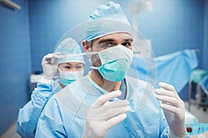 Nurse helping a surgeon in tying surgical mask