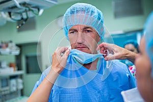 Nurse helping a surgeon in tying surgical mask