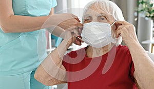 Nurse Helps Elderly Woman Put On Medical Face Mask