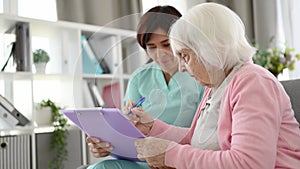 Nurse Helps Elderly Woman Sign Health Documents
