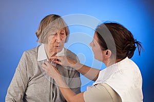Nurse helps a senior woman with dressing