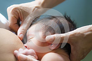 Nurse heps a mother breastfeeding her newborn baby