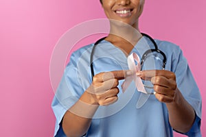 Nurse holding breast cancer awareness pink ribbon with both hands