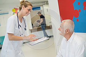 Nurse holding clipboard talking to patient