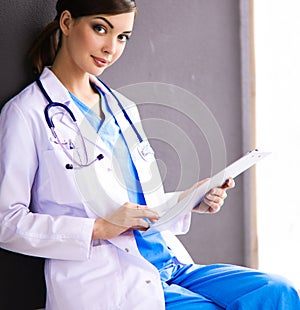 Nurse holding folder and taking notes - sitting on grey background