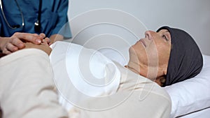 Nurse holding hand of cancer patient, thankful female looking at hospice worker