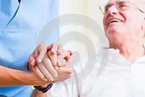 Nurse holding hand of senior man in rest home photo