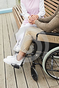 Nurse holding hands of man in wheelchair