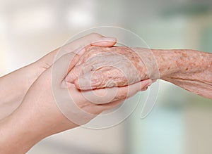 Nurse holding old patient hand