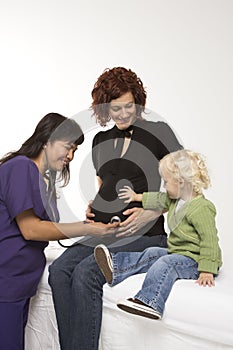 Nurse holding stethoscope on pregnant woman's belly.