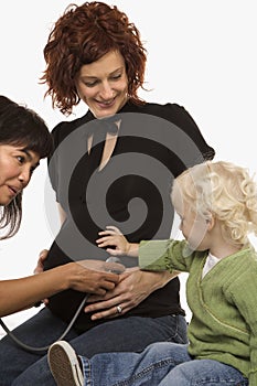 Nurse holding stethoscope on pregnant woman's belly.