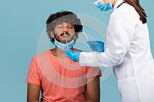 Nurse holding swab, making nasal PCR coronavirus test for man