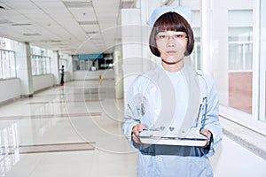 Nurse holding a tray, standing in a hospital corri