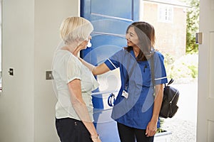 Nurse on home visit greets senior woman at her front door