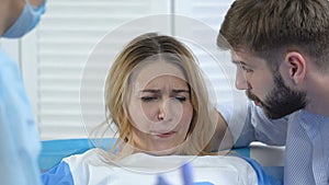 Nurse and husband comforting pregnant woman breathing deeply during contraction