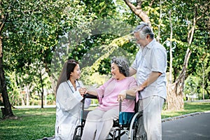 Nurse looking at elderly patient in a wheelchair. Doctor talking to old