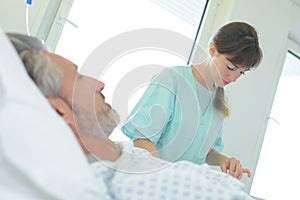 nurse looking through male patients notes in hospital bed
