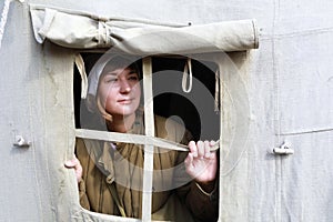 Nurse looks out of  window of tent hospital