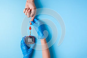 Nurse making a blood test. Man`s hand with red blood drop with Blood glucose test strip and Glucose meter