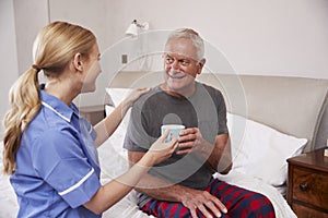 Nurse Making Home Visit To Senior Man In Bed