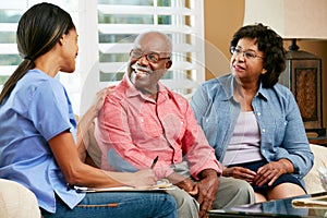 Nurse Making Notes During Home Visit With Senior Couple