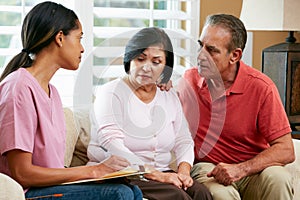 Nurse Making Notes During Home Visit With Senior Couple