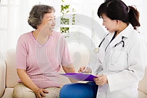 Nurse Making Notes During Home Visit With Senior woman