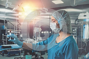 nurse in mask and gloves holding a syringe with medicine and waiting for a patient in surgery.