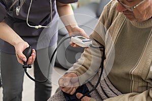 Nurse measure high blood pressure of a sick senior mature male patient in medical clinic closeup. Doctor checking